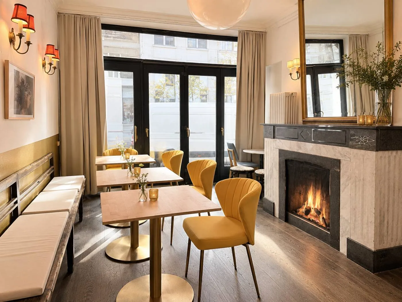 Kaminzimmer im Maison Marsil mit brennendem Kamin, gelben Samtstühlen und Messingtischen