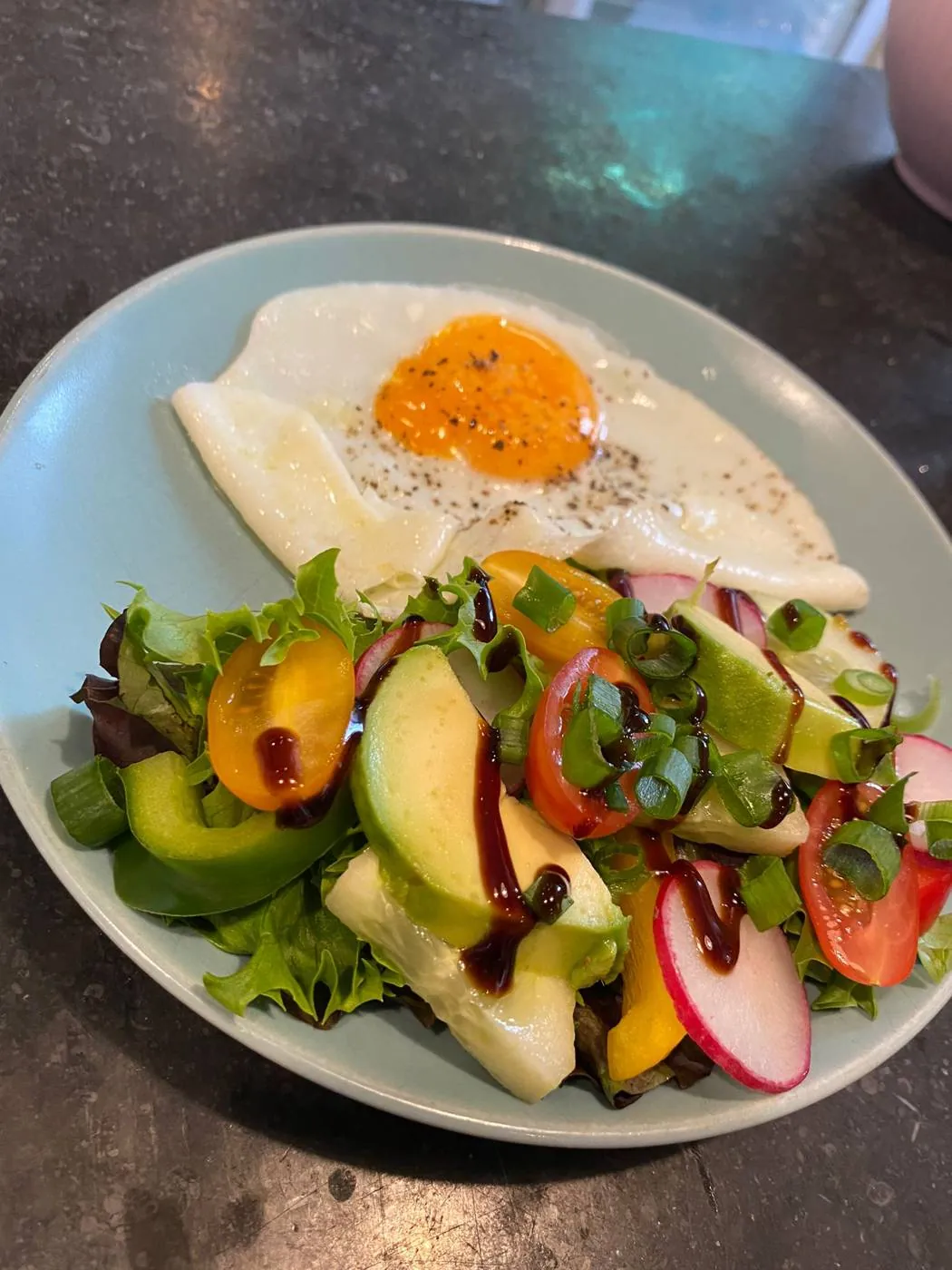 Spiegelei mit Salat, Avocado und Radieschen auf blauem Teller im Maison Marsil